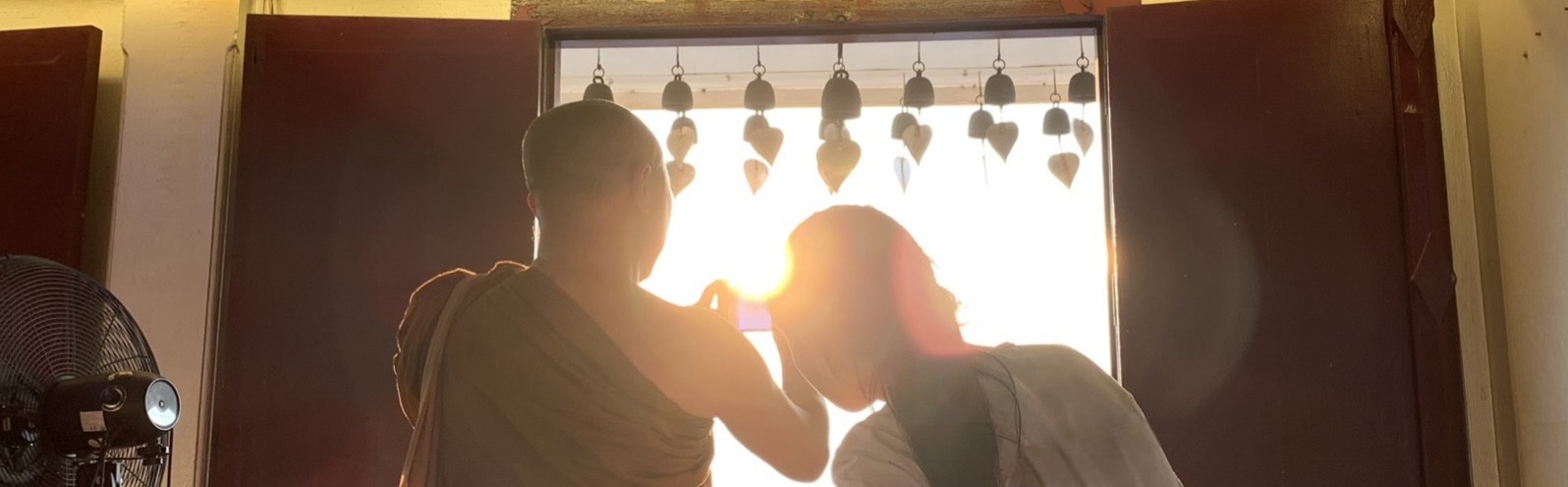 タイのお寺で夕日を撮影する僧侶と女学生